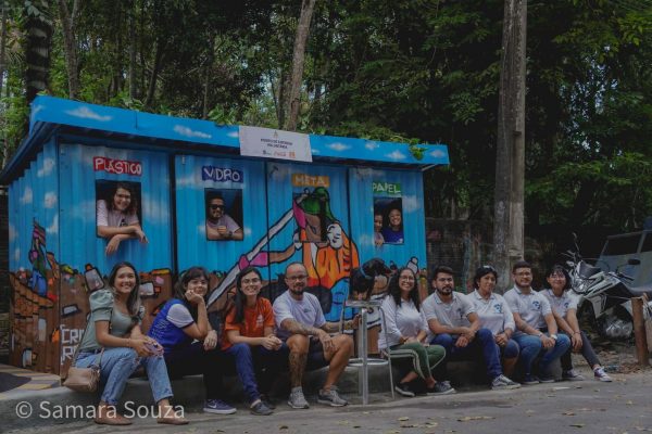 Pessoas sentadas em frente ao Ponto de Entrega Voluntária, instalado na Marina do Davi, terminal fluvial situado na zona Oeste de Manaus.